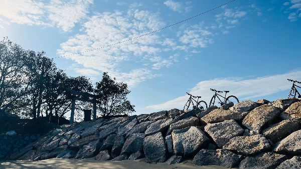 石積みの防波堤にとめられた2台の自転車と、青空