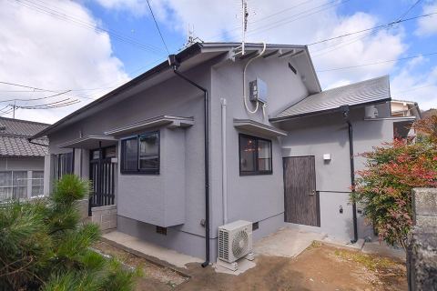 GuestHouse YULLATの黒い外観と青空