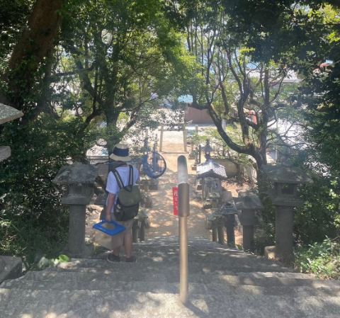 木漏れ日の石段と灯籠の並ぶ参道を下りる人。島四国の風景